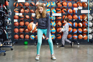 Children with basketballs in sport shop