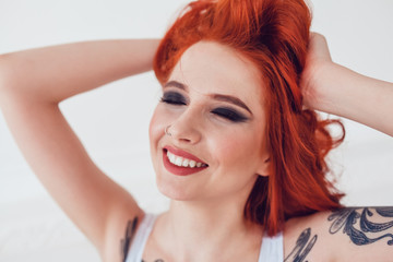 Portrait of a beautiful sexy girl with red hair and a tattoo. Woman with make-up and curls.
