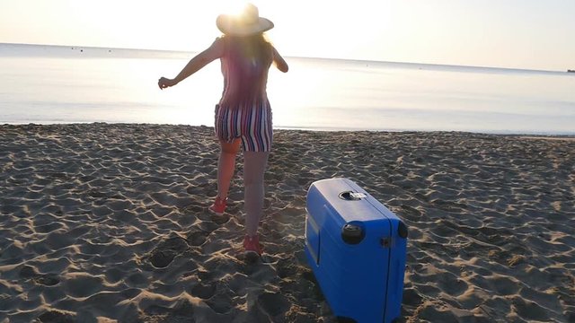 Happy woman travaler running on the beach back to camera