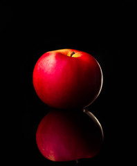 fresh red apple with droplets of water against black background reflection drops fresh splash action movement