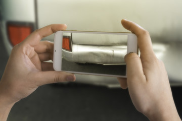 Young women using smart phones to take photos of accident insurance claims.