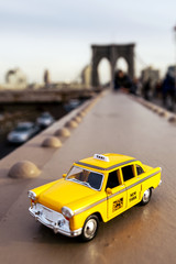 Model of a classic yellow taxi on a steel beam on Brooklyn Bridge.