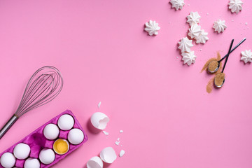 Bakery background frame. Cooking ingredients - egg, sugar, over pink background. Romantic cooking theme. Top view, copy space.