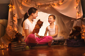 Obraz na płótnie Canvas Happy boy and girl playing at home in a tent