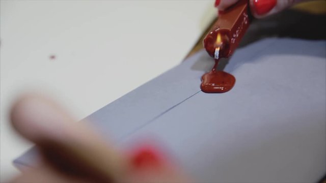 Girl put a seal with a sealing wax.Red wax seal or signet on lilac envelope.