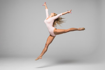 young modern gymnast dancer jumping on white background
