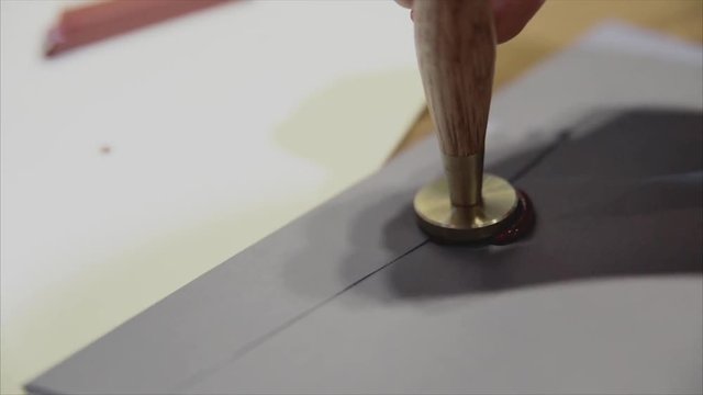 Girl put a seal with a sealing wax.Red wax seal or signet on lilac envelope.