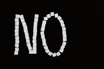 Word no made from white sugar cubes. Isolated on a black background.