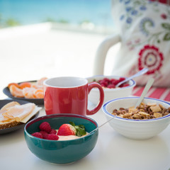 Healthy and delicious breakfast on the balcony with beautiful ocean view. Yogurt with fruit and organic berries, cereal and cheese for morning meal. Coffee time. Vacation by the sea.