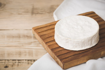 Fototapeta na wymiar Camembert cheese on wooden board. Serving French homemade soft cheese. Food concept