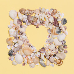Sea shells frame with space for text on yellow background.
