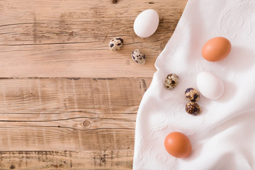 Top view on quail eggs on a wooden background and textile. Easter festive background. Flat lay.
