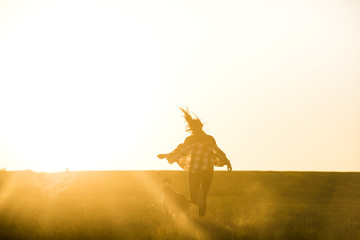 Silhouette of Young Woman and Pet Dog playing at sunset