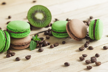 Green and brown french macarons with kiwi, coffee beans and mints decorations