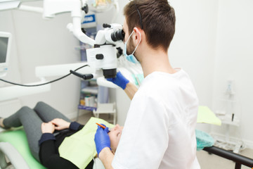 Naklejka na ściany i meble Male dentist is looking through a microscope
