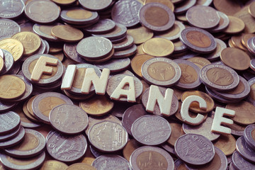 wood text FINANCE on coins background , business and finance concept