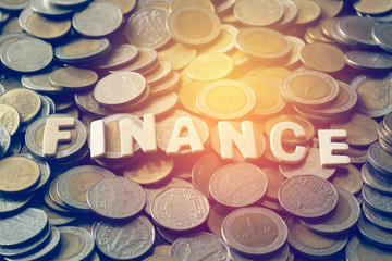 wood text FINANCE on coins background , business and finance concept