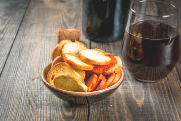 Assorted Italian brusquette crackers - with mushrooms, pesto and tomatoes - with wine in glass and bottle. On a wooden table. copy space