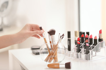 Professional makeup artist taking brush at beauty salon