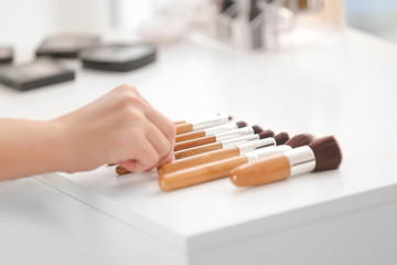 Professional makeup artist taking brush at beauty salon