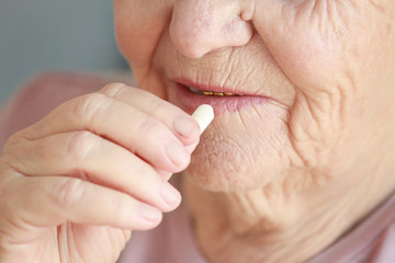 Elderly woman taking pill, closeup