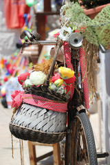 Colorful basket with flowers hanging on the steering wheel of a bicycle 