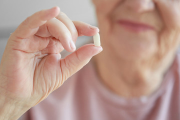 Hand of elderly woman with pill, closeup