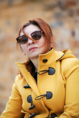 Woman wearing sunglasses and a yellow coat