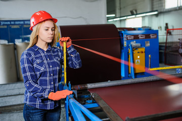 woman in red safety helmet at metal tile roof manufacturing factory