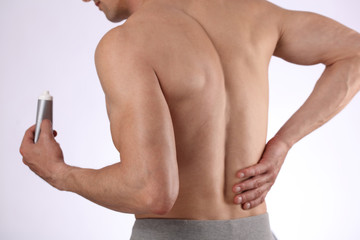 Fototapeta premium Man applying pain relieving cream, gel. Sport injury, Man with back, neck pain. Pain relief and health care concept.