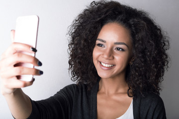 Portrait of young smiling woman taking selfie with smartphone