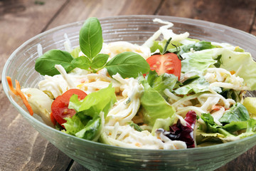 bowl of salad with vegetables and greens on wooden table