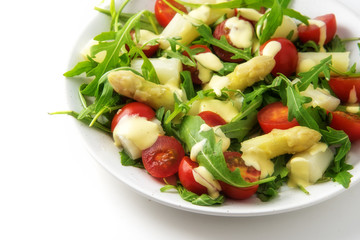 Salad of white asparagus, cocktail tomatoes and arugulaappetizer snack in italian colors on a white background, copy space