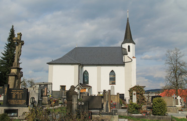 small white church and graveyard around it in Hodonovice, Czech Republic