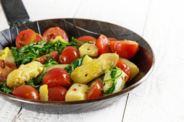 vegetable pan with fried asparagus, tomatoes and spinach on a white wooden table, low carb meal, selected focus, narrow depth of field