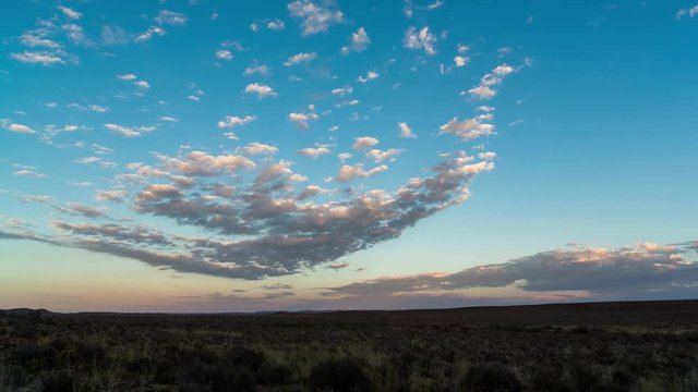 A peaceful static timelapse shot of slow moving scattered clouds at sunrise of a typical Karoo landscape with wide open vistas
