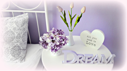 Interior arrangement on the bedside table: hydrangea, tulips and letters in purple tones. Filter: vignette