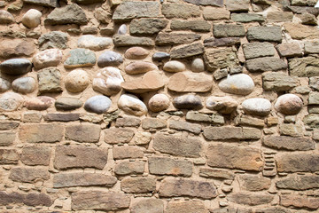 Round river stones in an ancient Native American wall among rectangular rocks