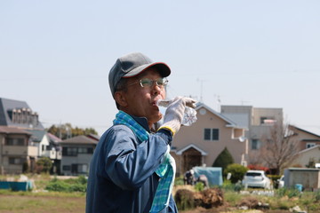 畑で水分補給するシニア