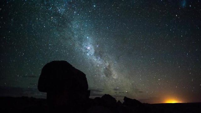 Linear pan and tilt timelapse of the rising Milky Way with silhouette rocks in the foreground with scattered clouds, starting at blue hour through the night until blue hour before sunrise, shot blowing out at the end available on request.