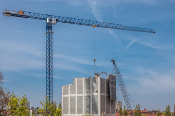 Großbaustelle in München - Kran hält Bagger, der Haus abreißt 