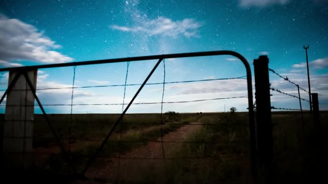 Linear timelapse at night time with a dramatic moonlit landscape scene in the Karoo, through a rusted farm gate with scattered clouds available on request.
