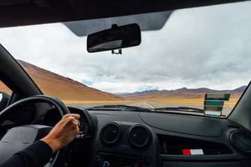 View from inside a car on the road next to mountains