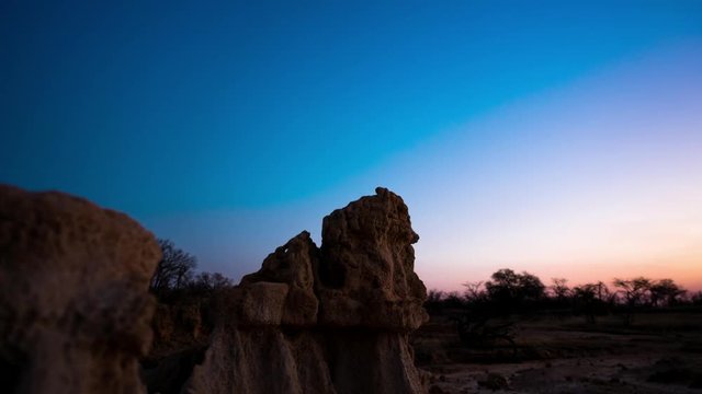 Linear, push-in holy grail timelapse of abstract landscape with eroded rocks while the sun is setting from day to night, while the Milky Way moves into the frame available on request.
