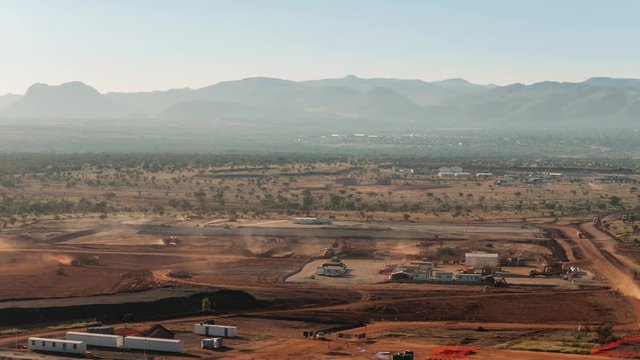 Static late afternoon timelapse of a construction site on a mine while earthworks is in progress with heavy load machinery, trucks and tippers