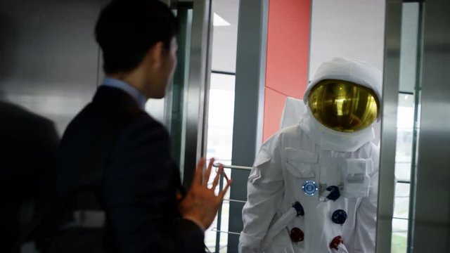  Astronaut taking the elevator with businessman in modern office building