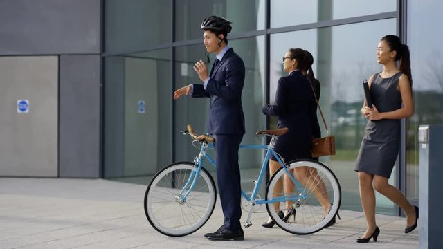  Businessman with bicycle leaving office at end of day & coworkers following