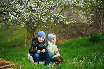 Naklejka na ściany i meble Cheerful brother and sister on a spring walk near flowering trees