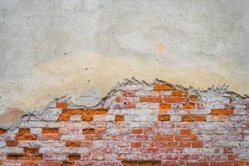 Grunge brick wall of the old house. Textured background. Remains of old plaster