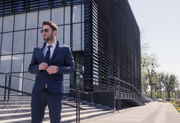 one young man, buttoning shirt, street modern building